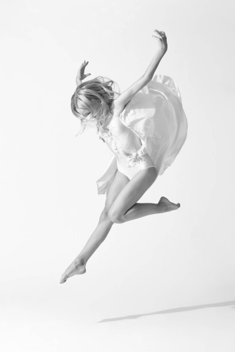 Ballet dancer performing a graceful jump in a studio setting.