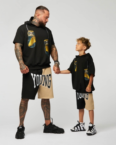 Tattooed fighter and his son wearing matching streetwear outfits in a professional studio.